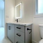 A clean bathroom featuring a sink, toilet, and mirror, showcasing a modern and functional design
